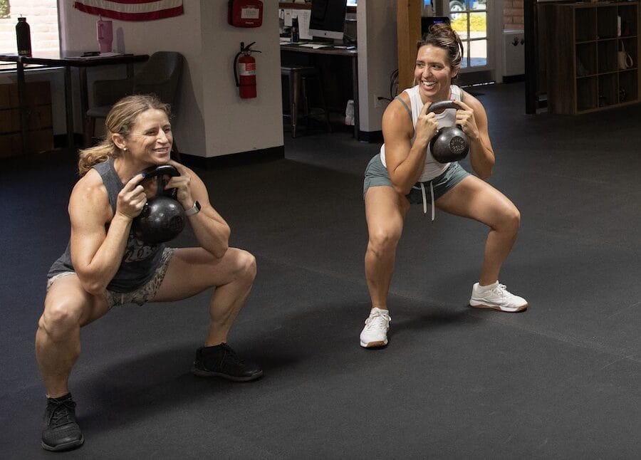 Smiling woman lifting weights in a bright gym, representing creatine benefits for women